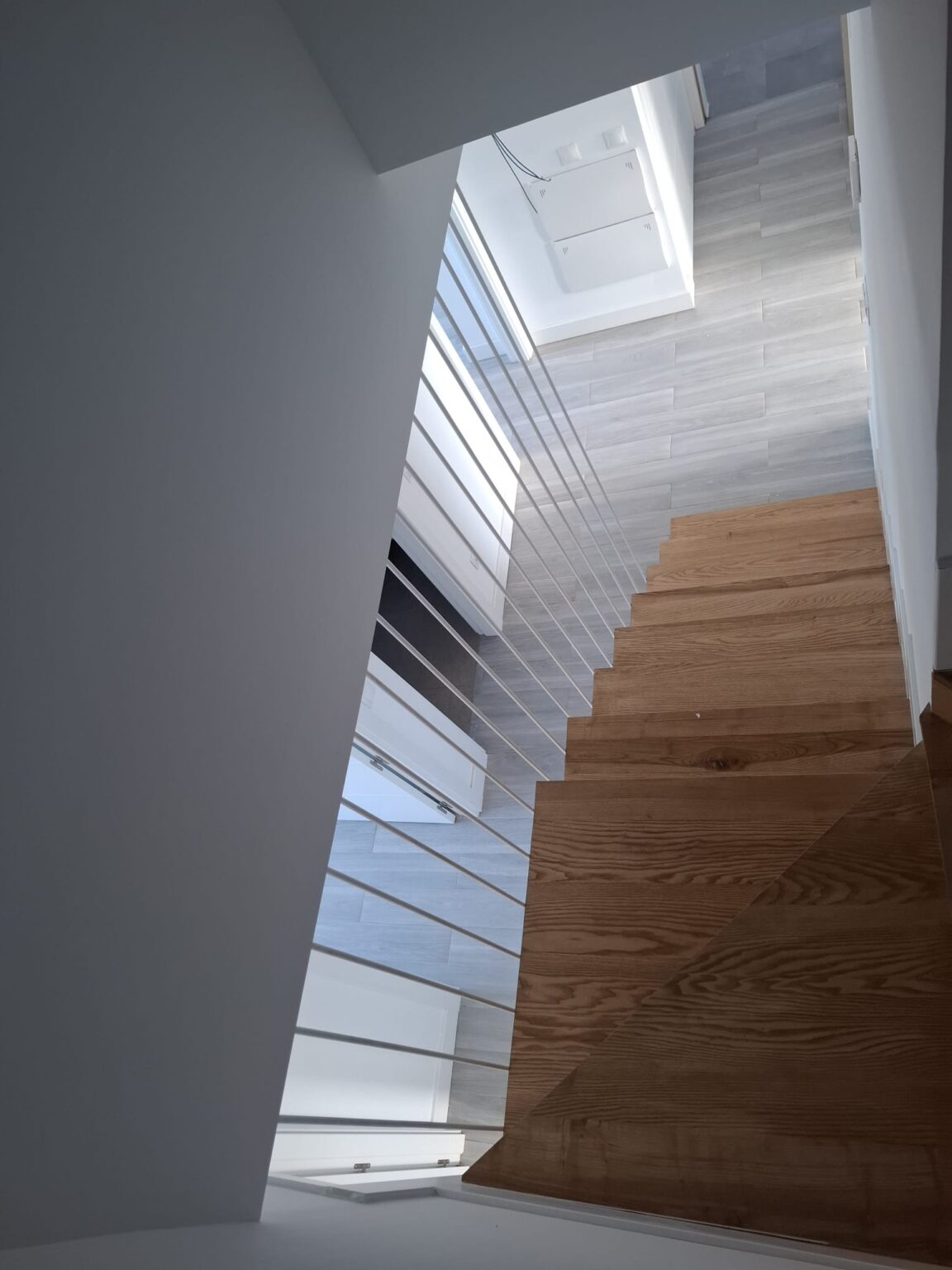 Escalera interior moderna con iluminación natural tras reforma de vivienda en Madrid