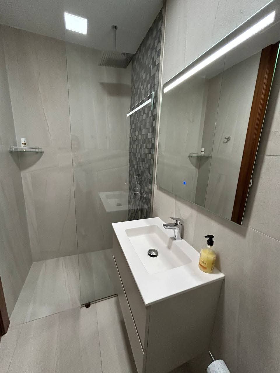 Baño moderno con plato de ducha y lavabo suspendido reformado por empresa de reformas en Madrid