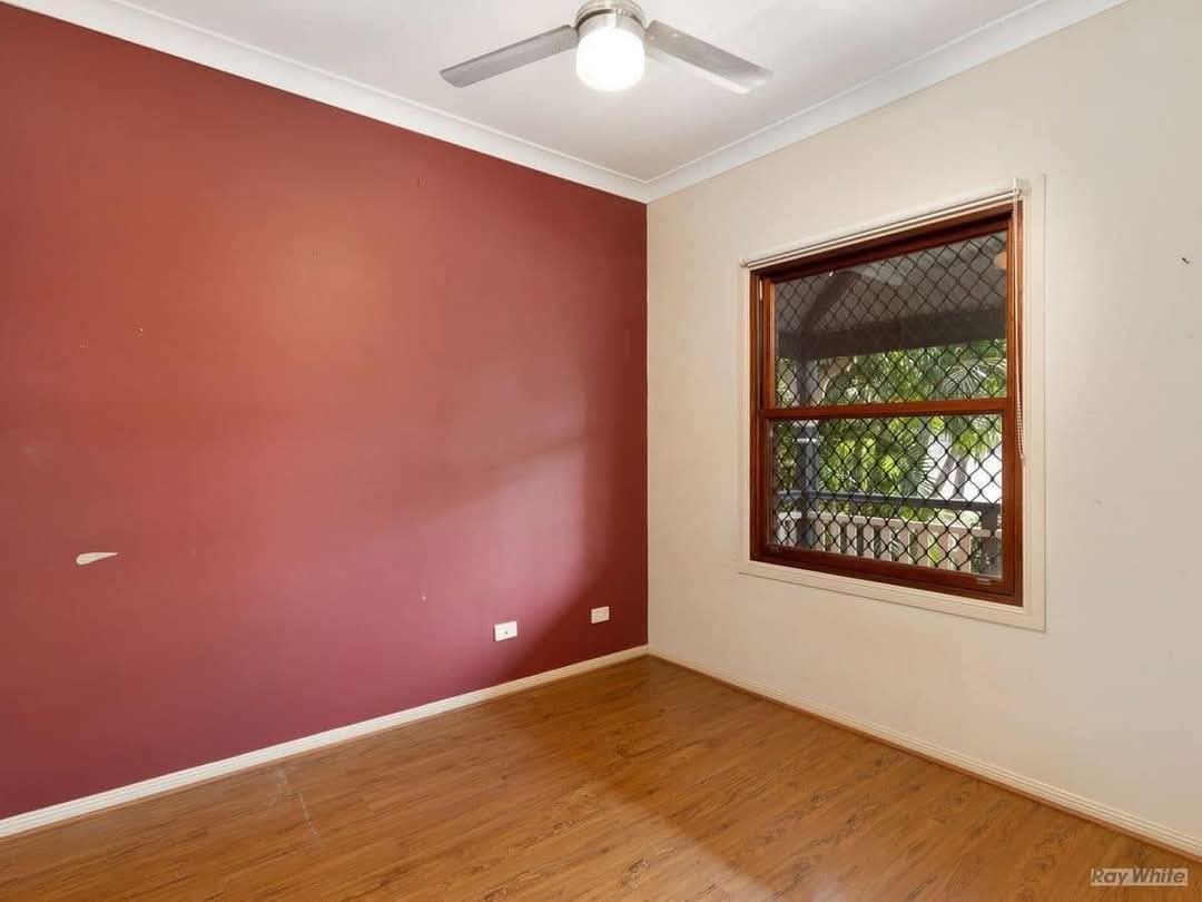 Dormitorio reformado con pared roja y suelo de madera realizado por Reformas M A en Madrid