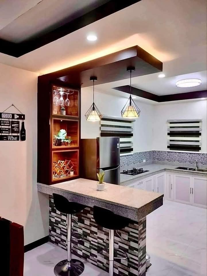 Cocina reformada con barra americana y estanterías decorativas en vivienda de Madrid