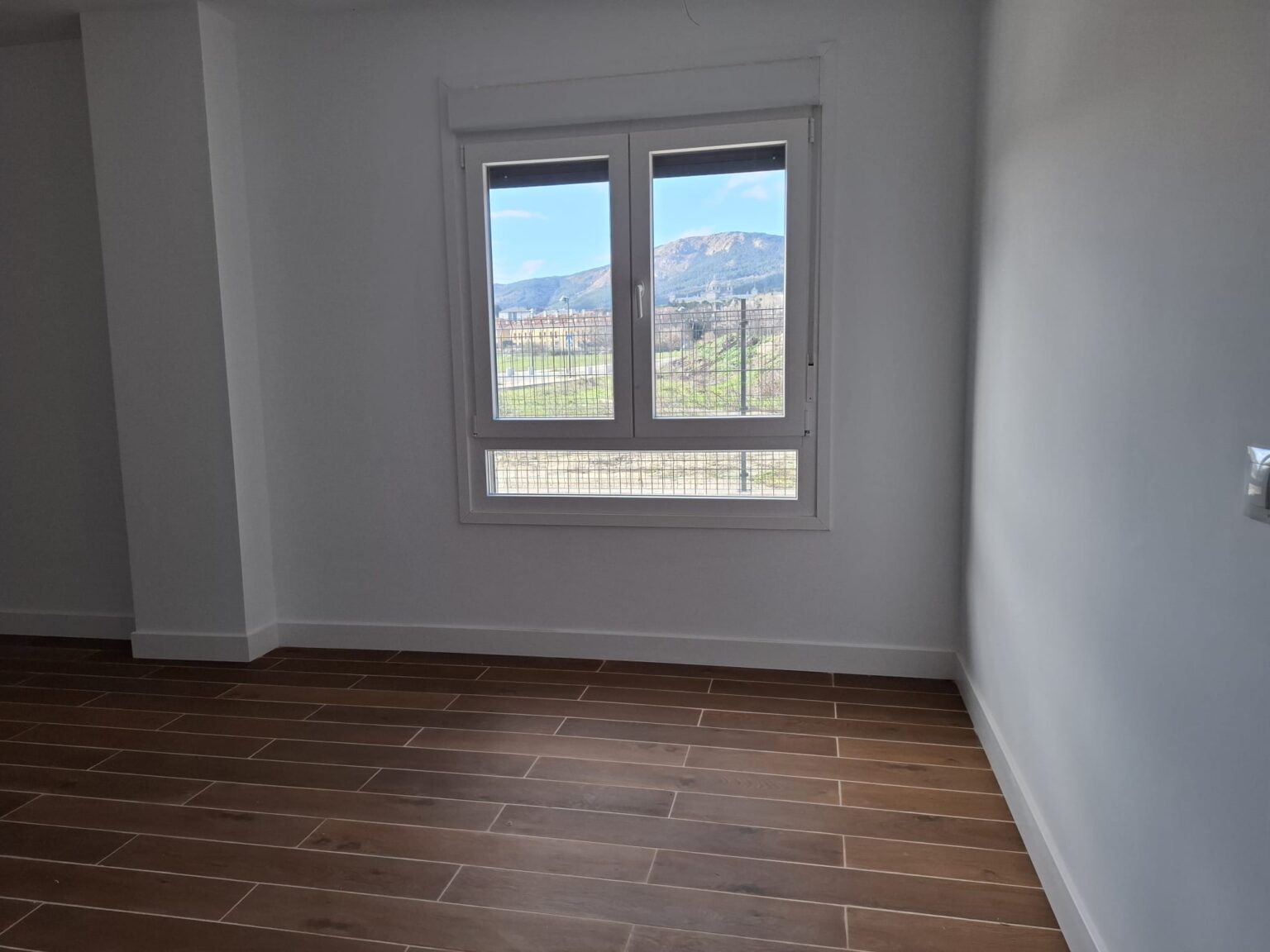 Dormitorio luminoso con suelo cerámico tras reforma de vivienda realizada en Madrid