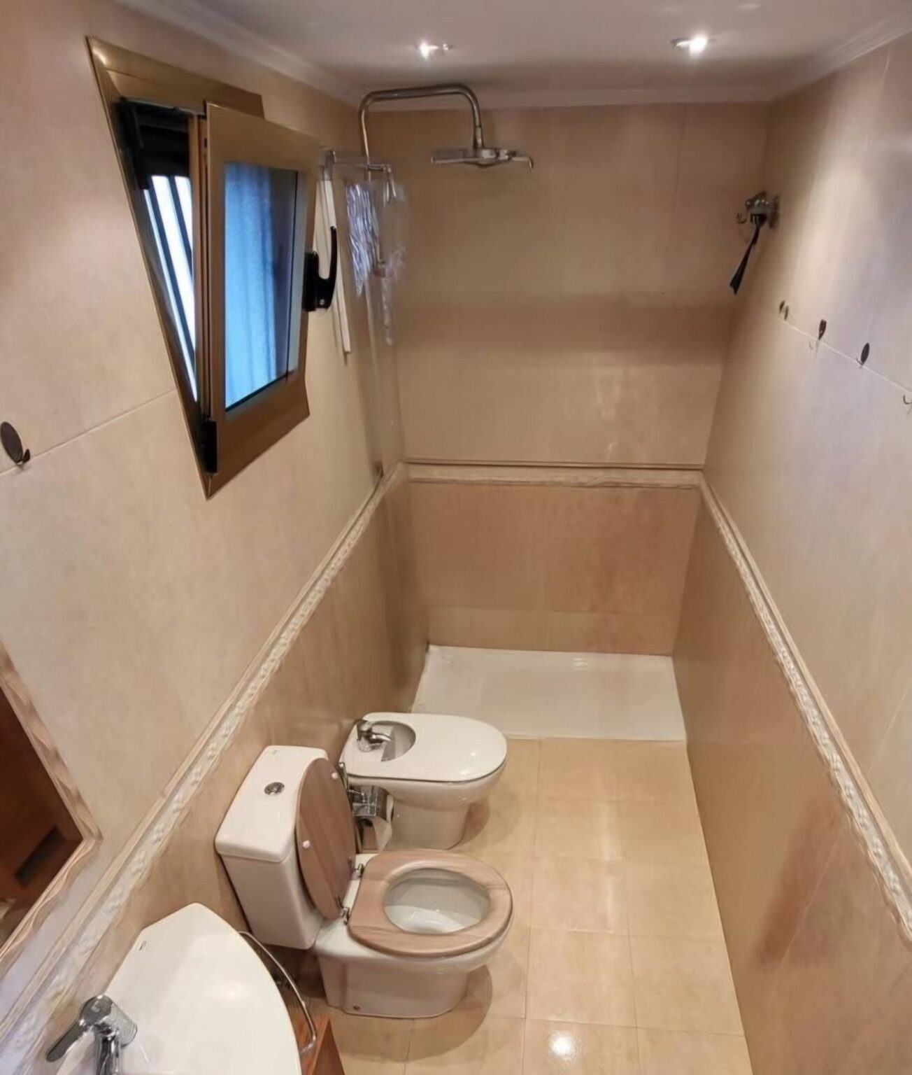 Baño reformado con azulejos beige y sanitarios instalados en vivienda de Madrid