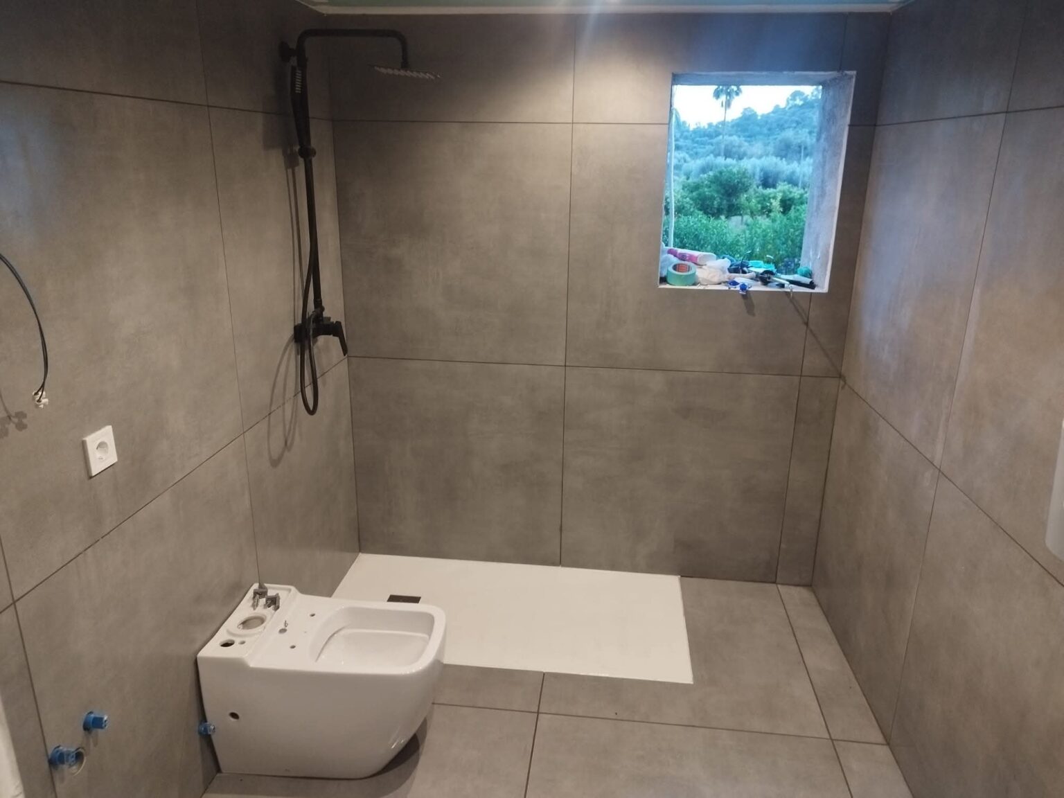 Baño moderno con plato de ducha y revestimiento cerámico tras reforma en Madrid