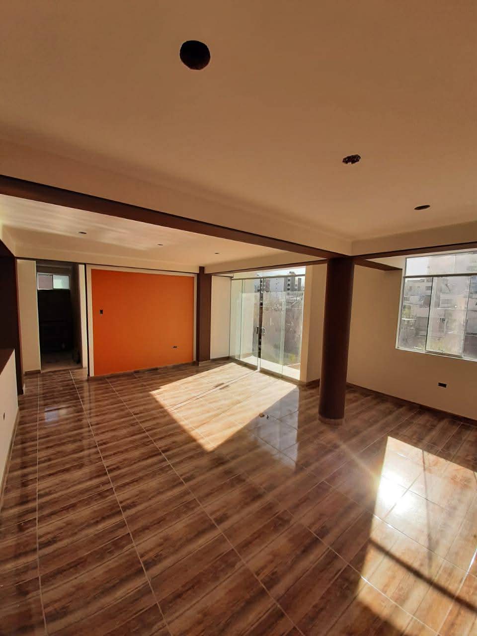 Salón amplio con suelo de madera y grandes ventanales tras reforma integral en vivienda de Madrid