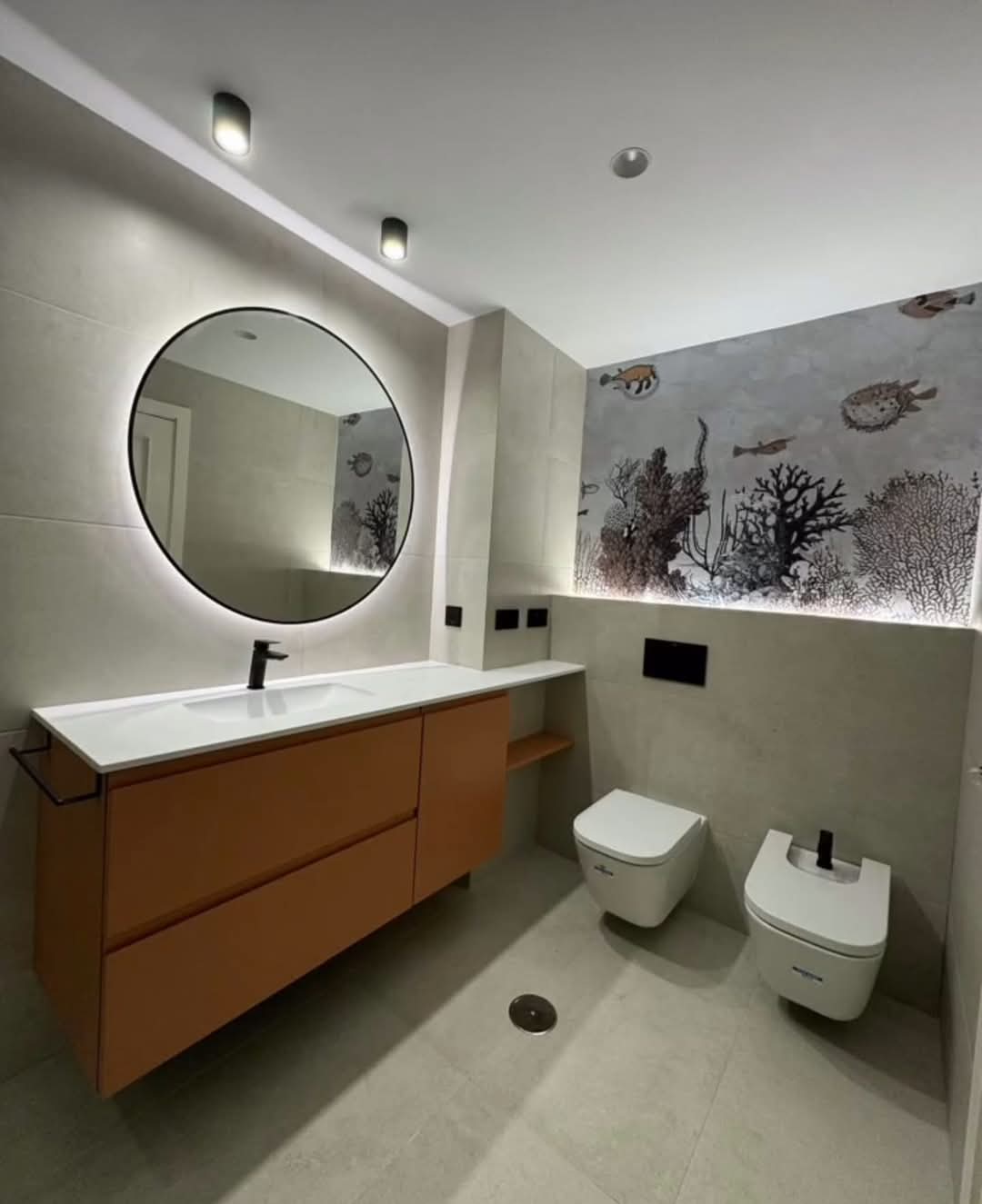 Baño moderno con lavabo doble y espejo iluminado tras reforma integral en Madrid