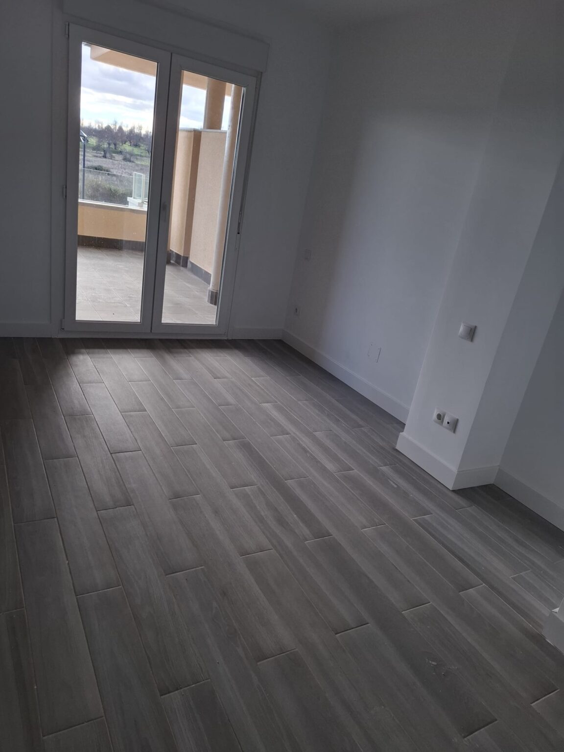 Salón reformado con suelo laminado efecto madera en vivienda de Madrid